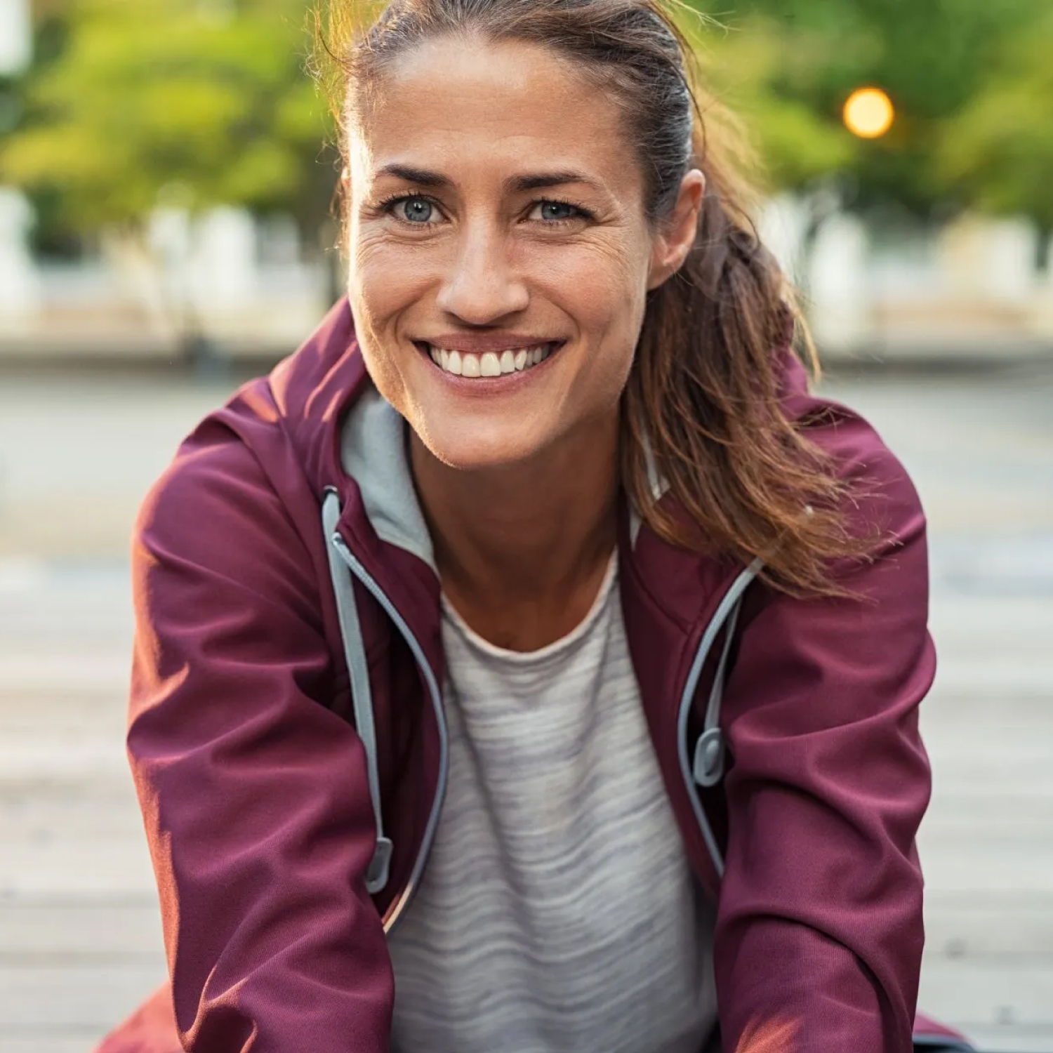 Smiling woman in athletic attire outdoors.