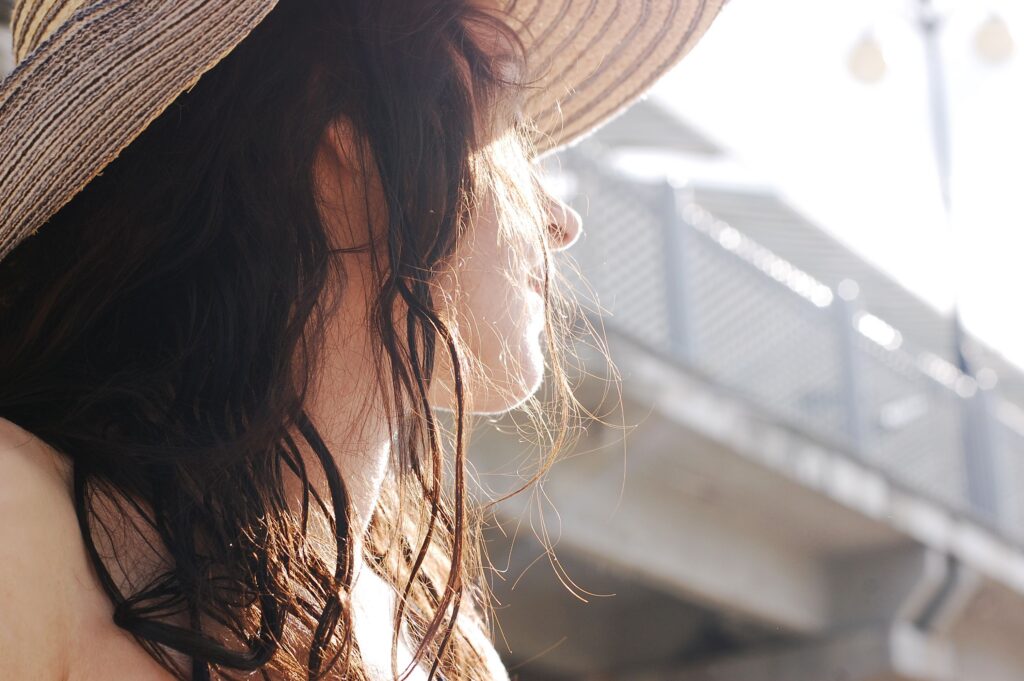 Woman wearing sun hat outdoors to protect sensitive skin during a psoriasis eczema summer flare