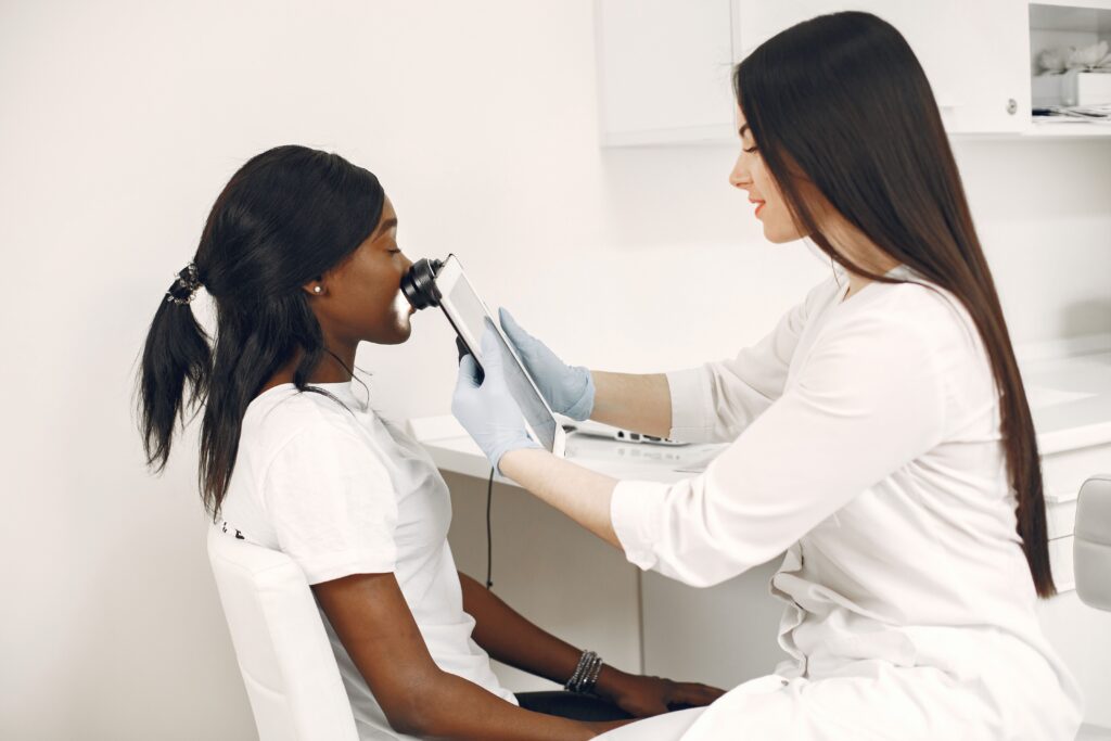 Dermatology provider examining a patient’s facial dark spots with a digital dermatoscope