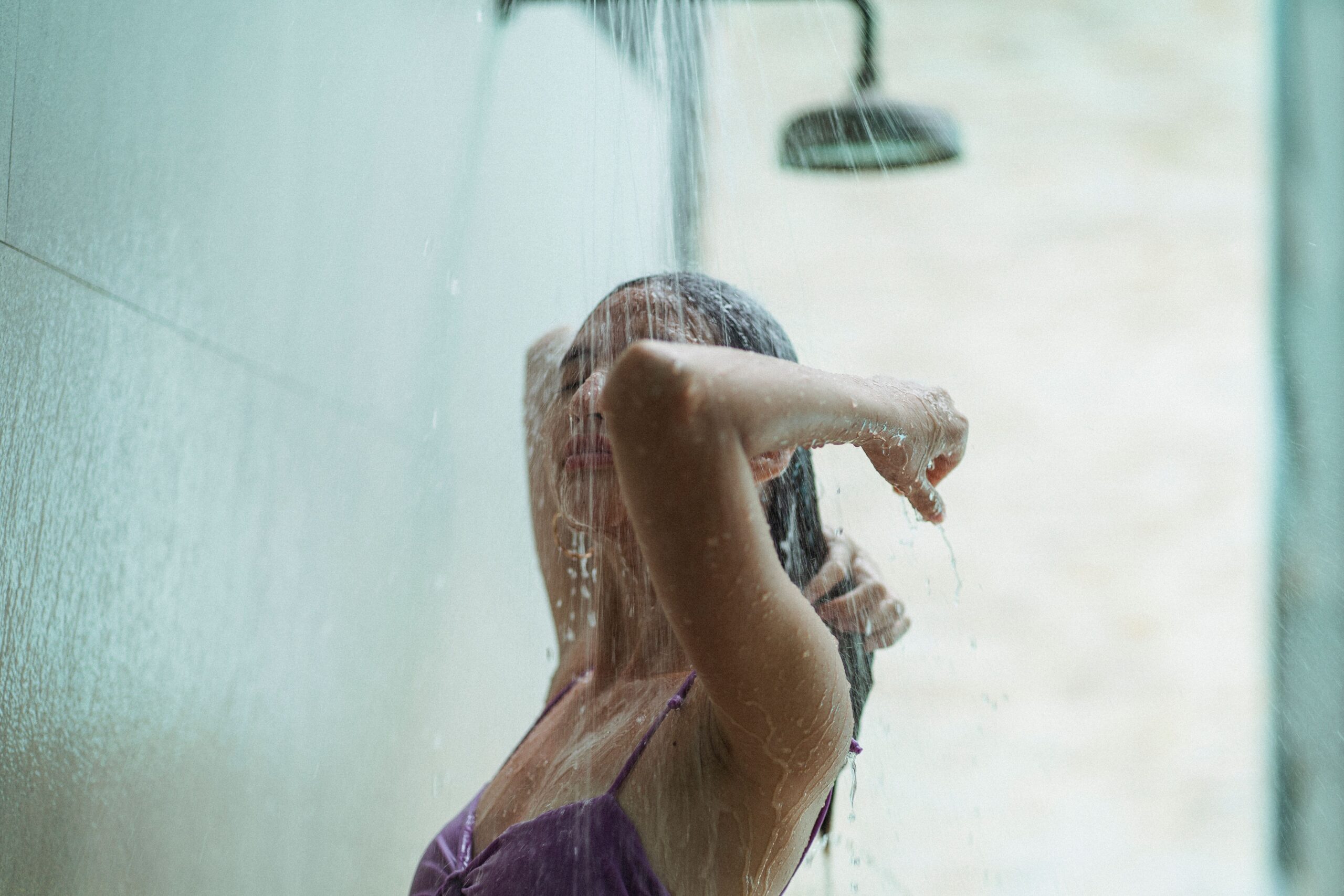 Woman taking a hot shower that can trigger eczema in fall by stripping natural skin oils